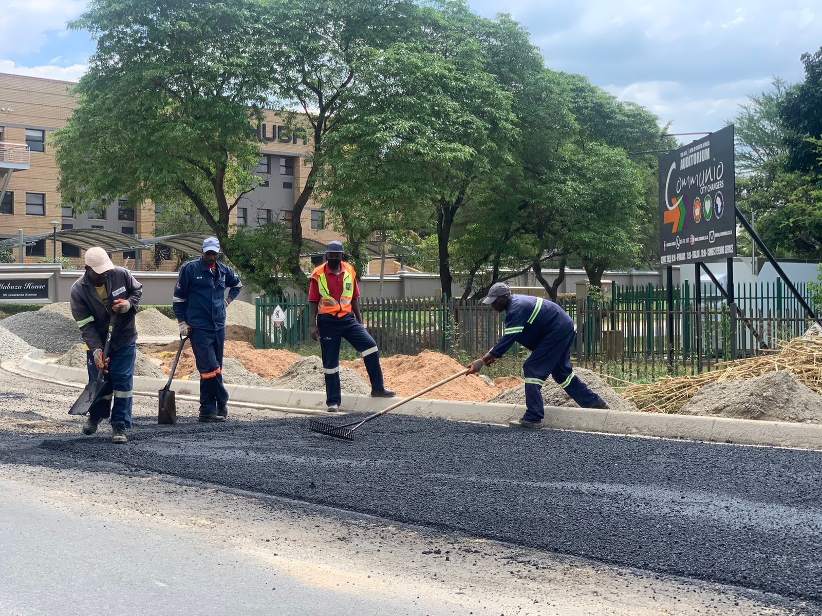 Crew raking and levelling hot asphalt
