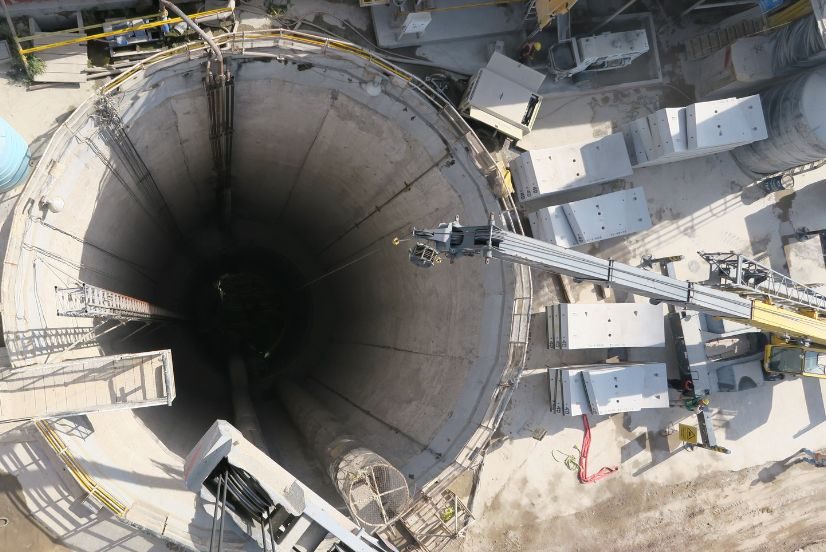 Crane lifting precast segments into a large concrete shaft