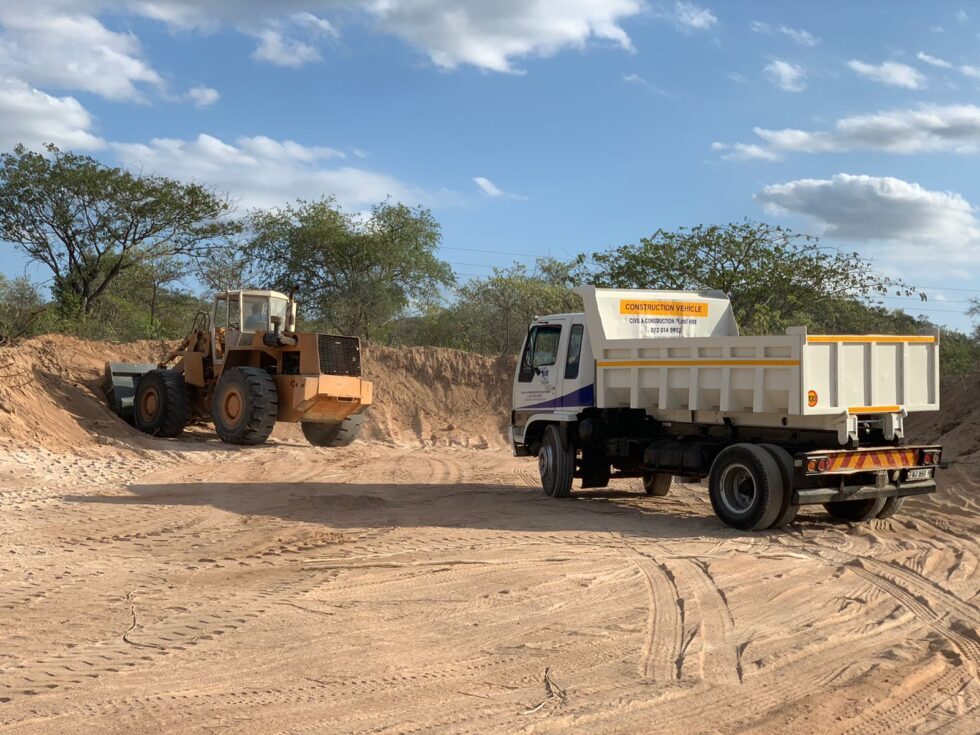Tipper truck and front-end loader on a borrow pit
